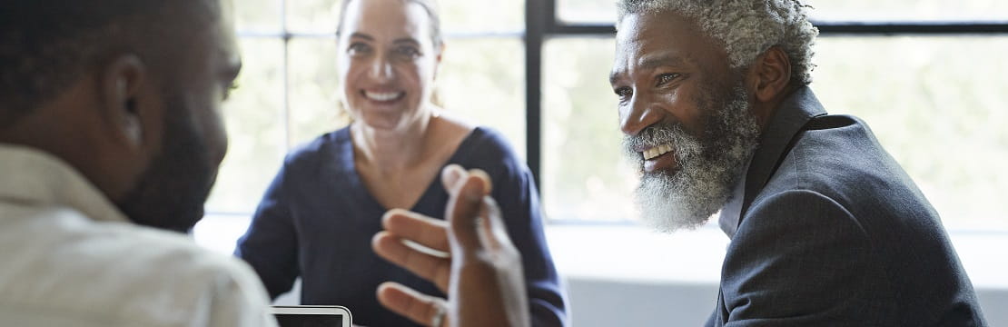 Businessman speaks with two other professionals in an office.